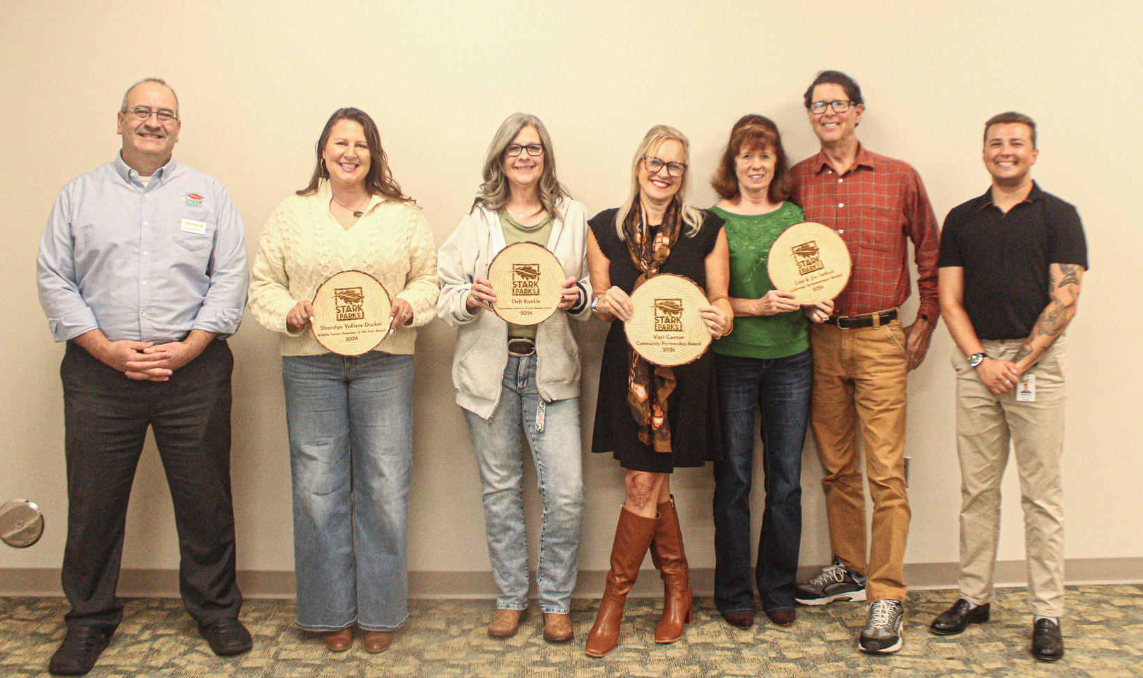 Volunteers holding wooden tree cookie awards
